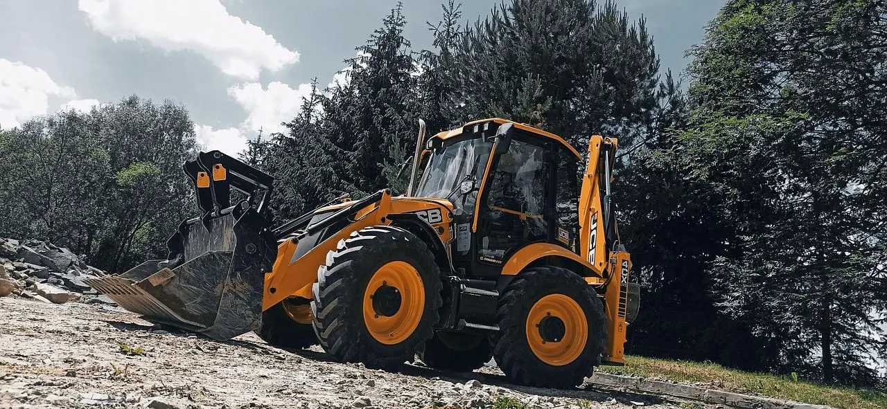 Koparko-ładowarka JCB na terenie robót ziemnych.